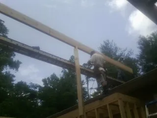 Carpenter setting a ridge beam over a new addition frame — Ice Dam Removal by Roofing Brothers in Starke