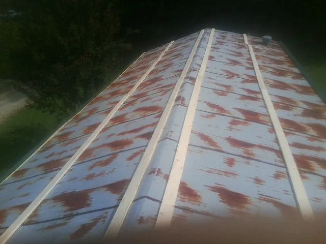 Rusted metal roof panels with new wood purlins before replacement — Storm Damage Roof Repair in Starke by Roofing Brothers
