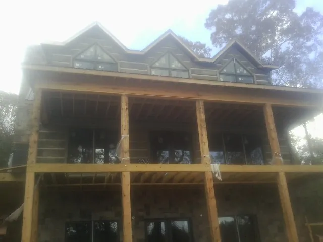 Dormers and porch framing on a large log home under construction — Roof Coating work by our crew in Starke