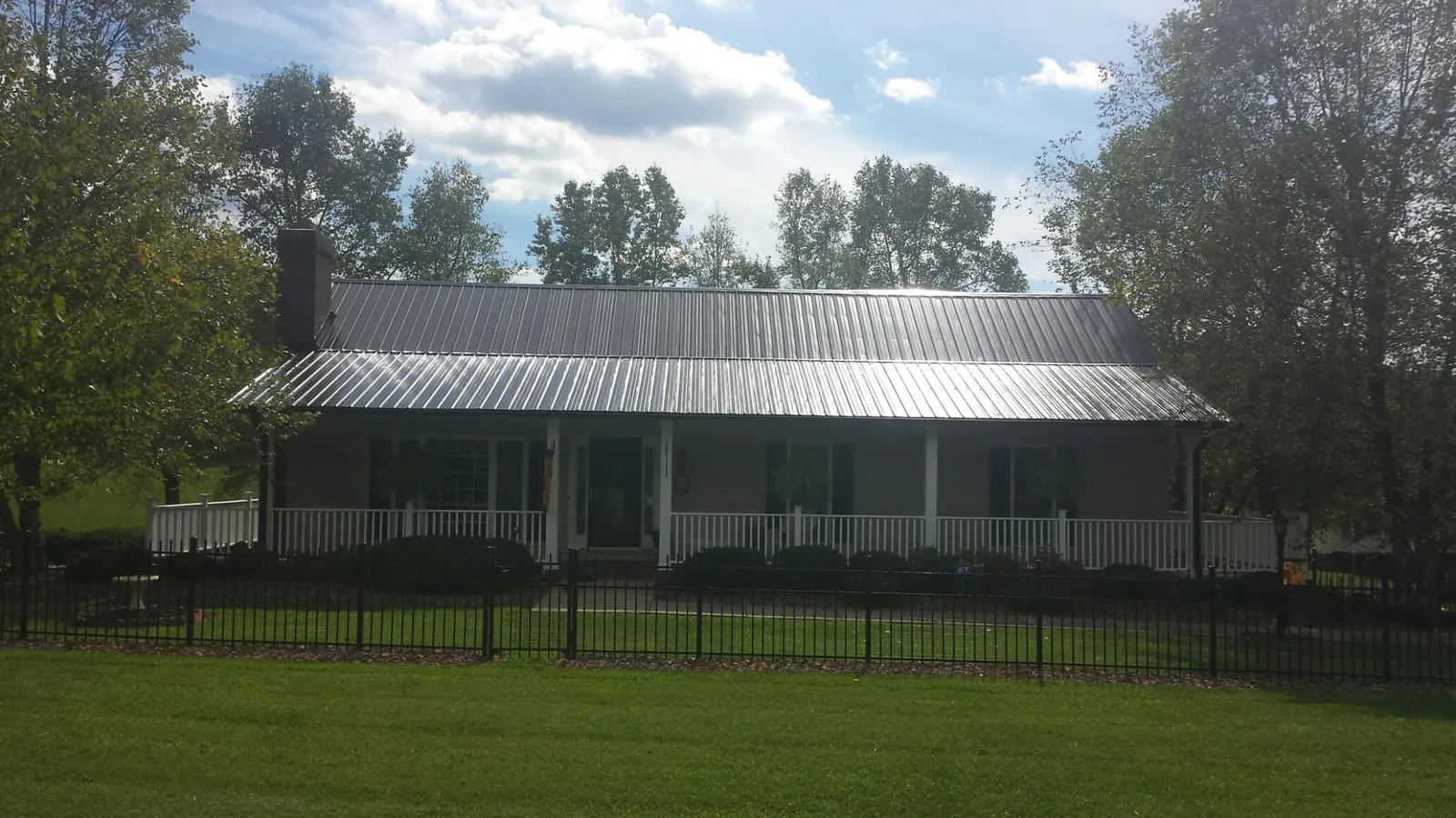 Gray metal roof on a brick ranch with a full width front porch — Gutter Guard Installation work by our crew in Starke