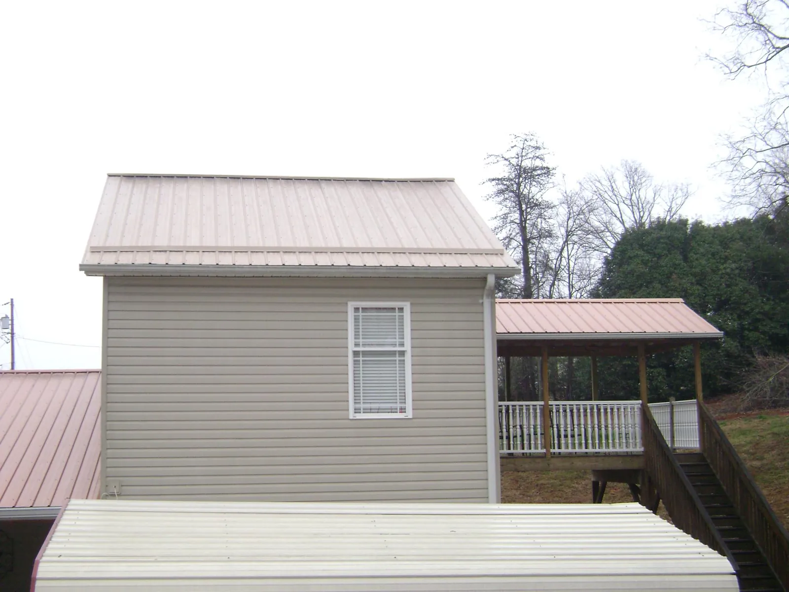 Tan metal roofs on a two story addition and attached porch, from a Roof Replacement job in Starke